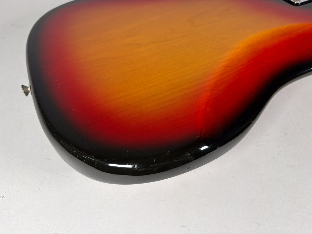 Close-up of the bass body's lower bout, showing the sunburst finish with visible checking and several chips along the bottom edge.