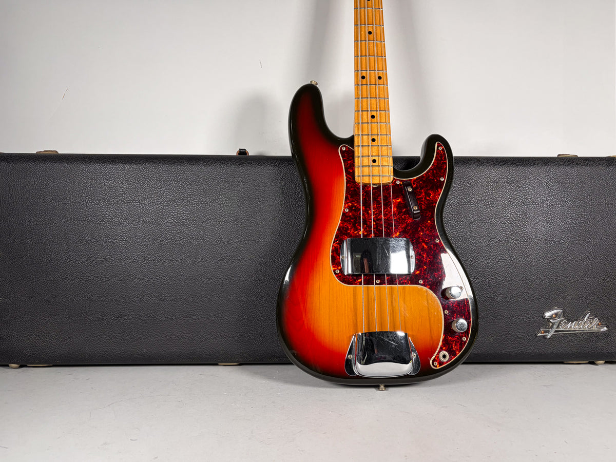 Sunburst bass with a maple neck, tortoise pickguard, chrome pickup and bridge covers, leaning against a black hard case.