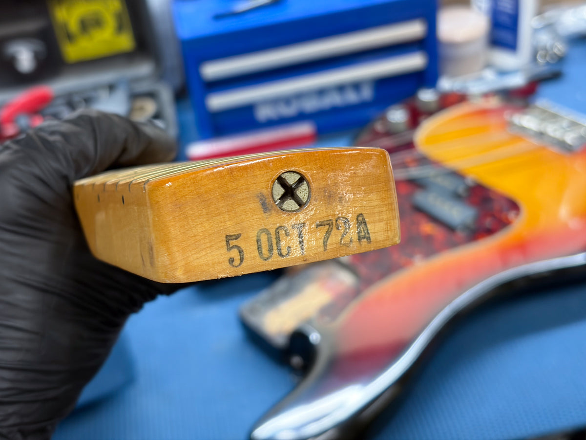 Close-up of the neck heel, showing a cross-head screw and "5 OCT 72A" stamped into the worn, light-brown wood.