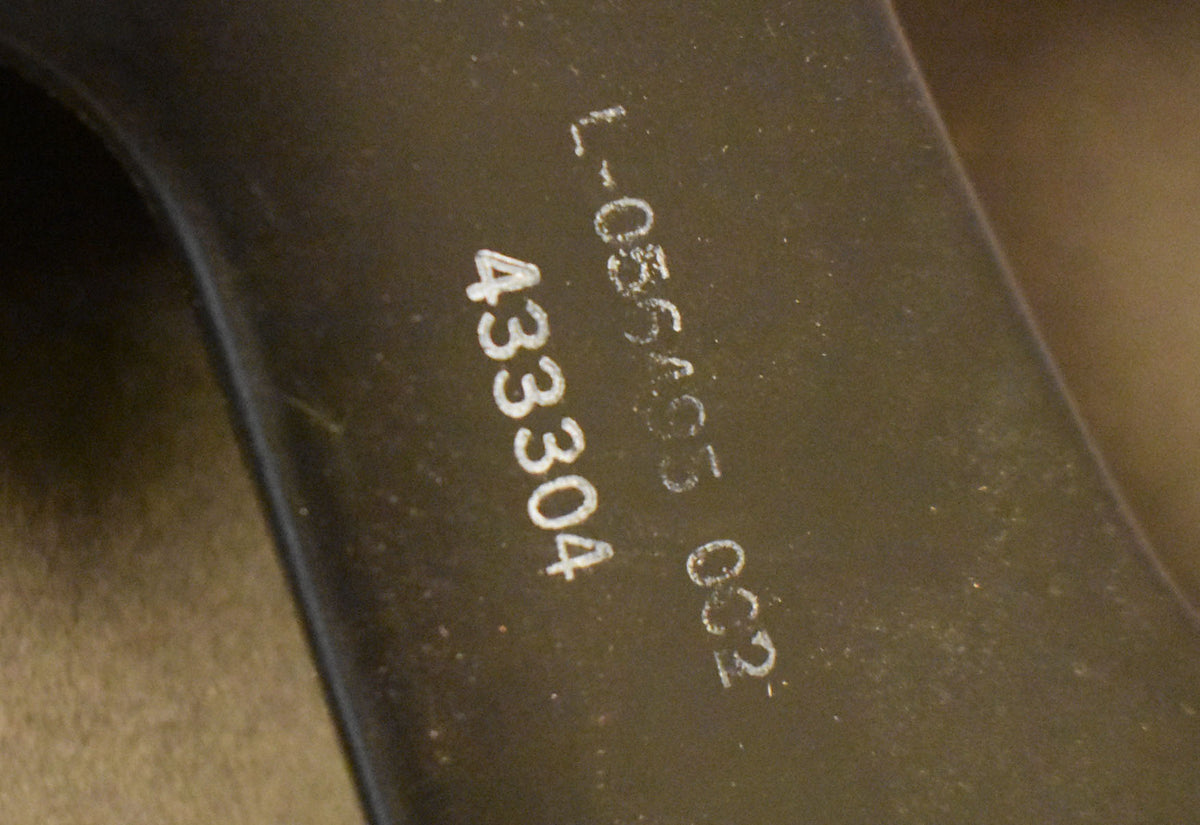Close-up of the speaker's dark gray metal frame, showing white stamped numbers and light dust on the textured surface.