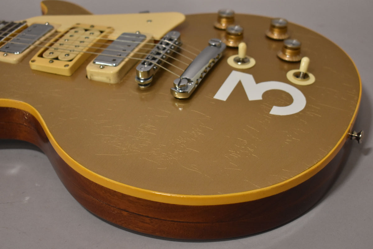 Close-up of the goldtop body, showing three cream mini-humbuckers, chrome hardware, four gold knobs, two cream toggle switches, and a large white "3" decal.