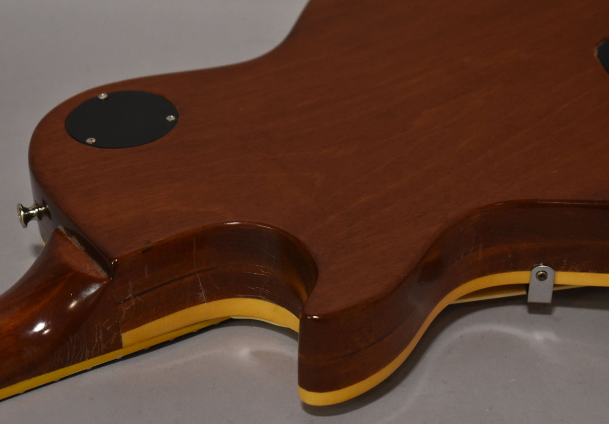 The guitar's dark brown back shows heavy finish checking and wear around the neck joint, with a black control cavity cover.