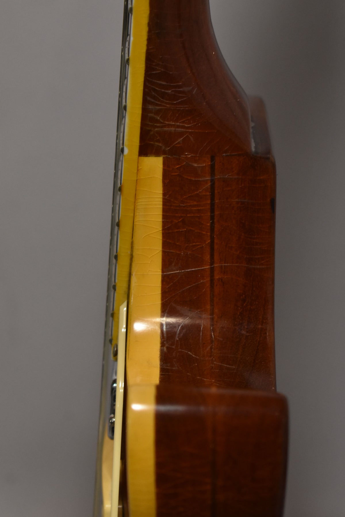 Close-up of the guitar's side, showing the goldtop finish with heavy checking and a dark brown back with vertical grain.