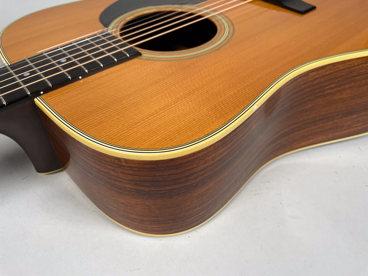 Close-up of the guitar's lower bout, showing the warm brown wood grain of the sides, a light finish chip on the upper curve, and cream binding.