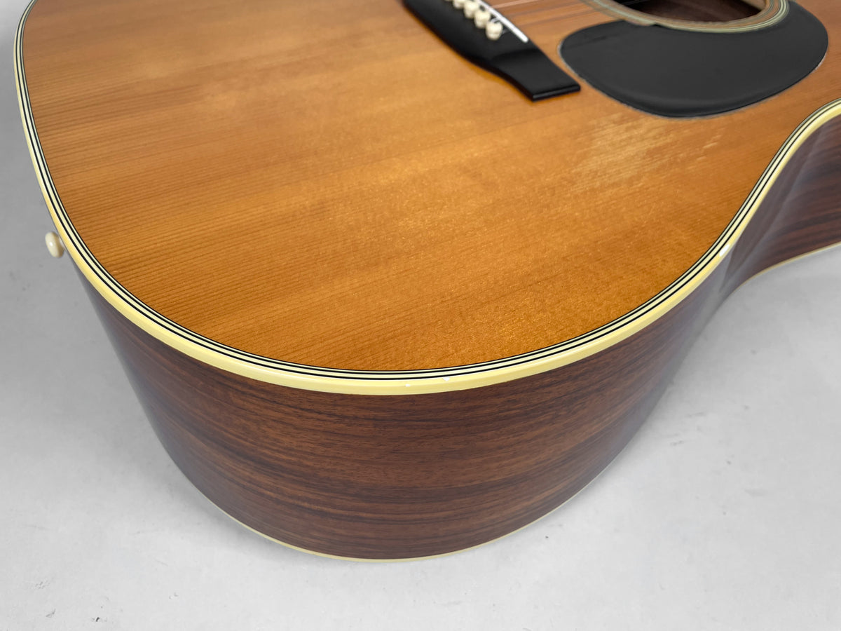Close-up of the guitar's lower bout, showing the light brown top, dark wood sides, and cream binding with thin black stripes.
