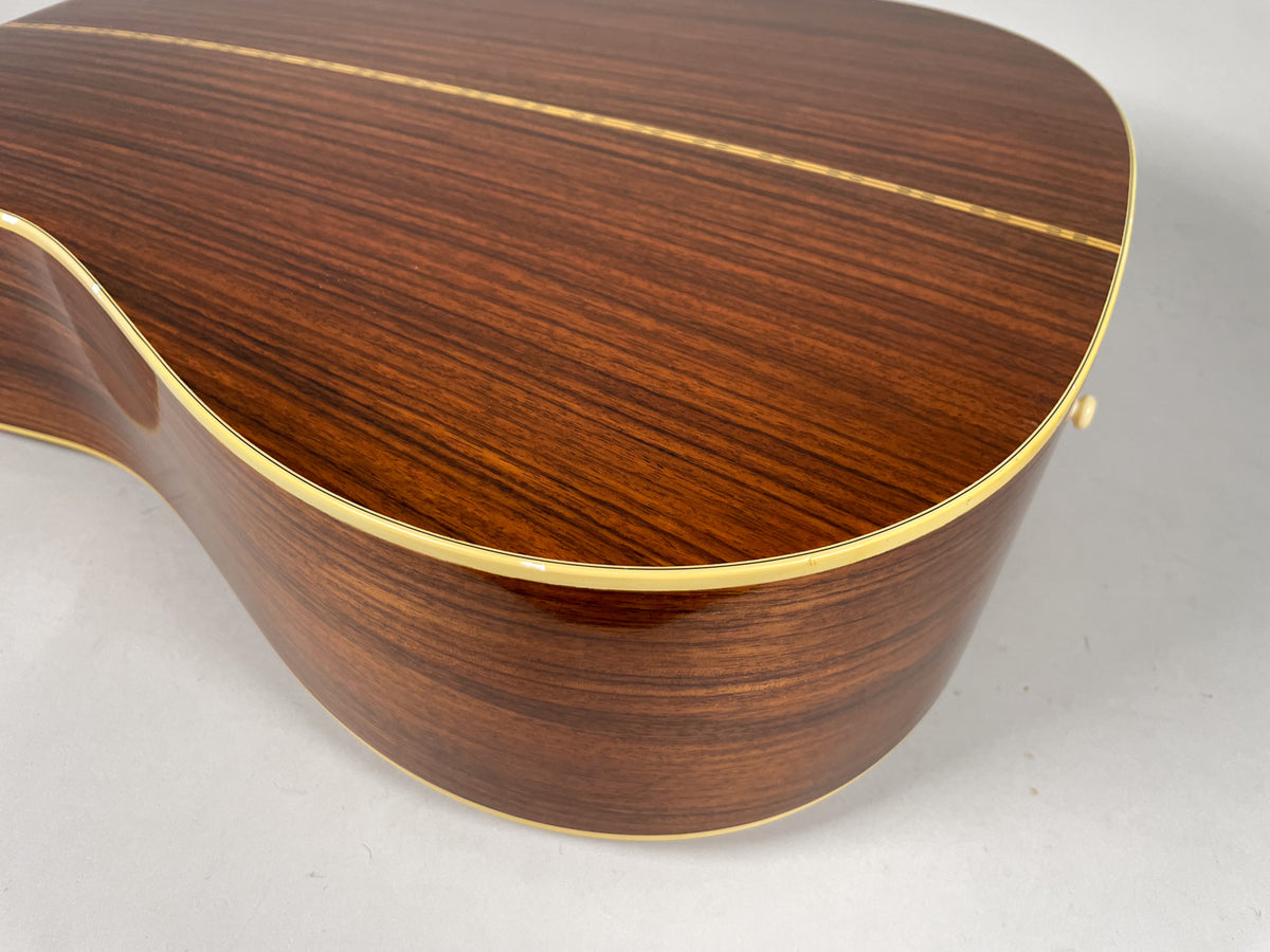 The guitar's dark wood back and side are visible from an overhead angle, showing a light binding and a few small dings.