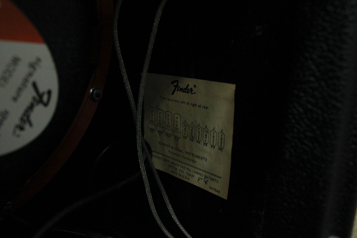 A close-up of the amp's interior, showing a faded tube chart label and a portion of a speaker with a red-orange rim.