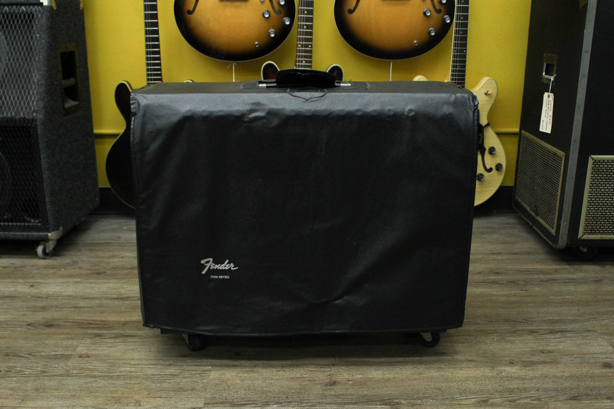 Front view of a black vinyl amplifier cover with a white script logo, a top handle, and four casters.