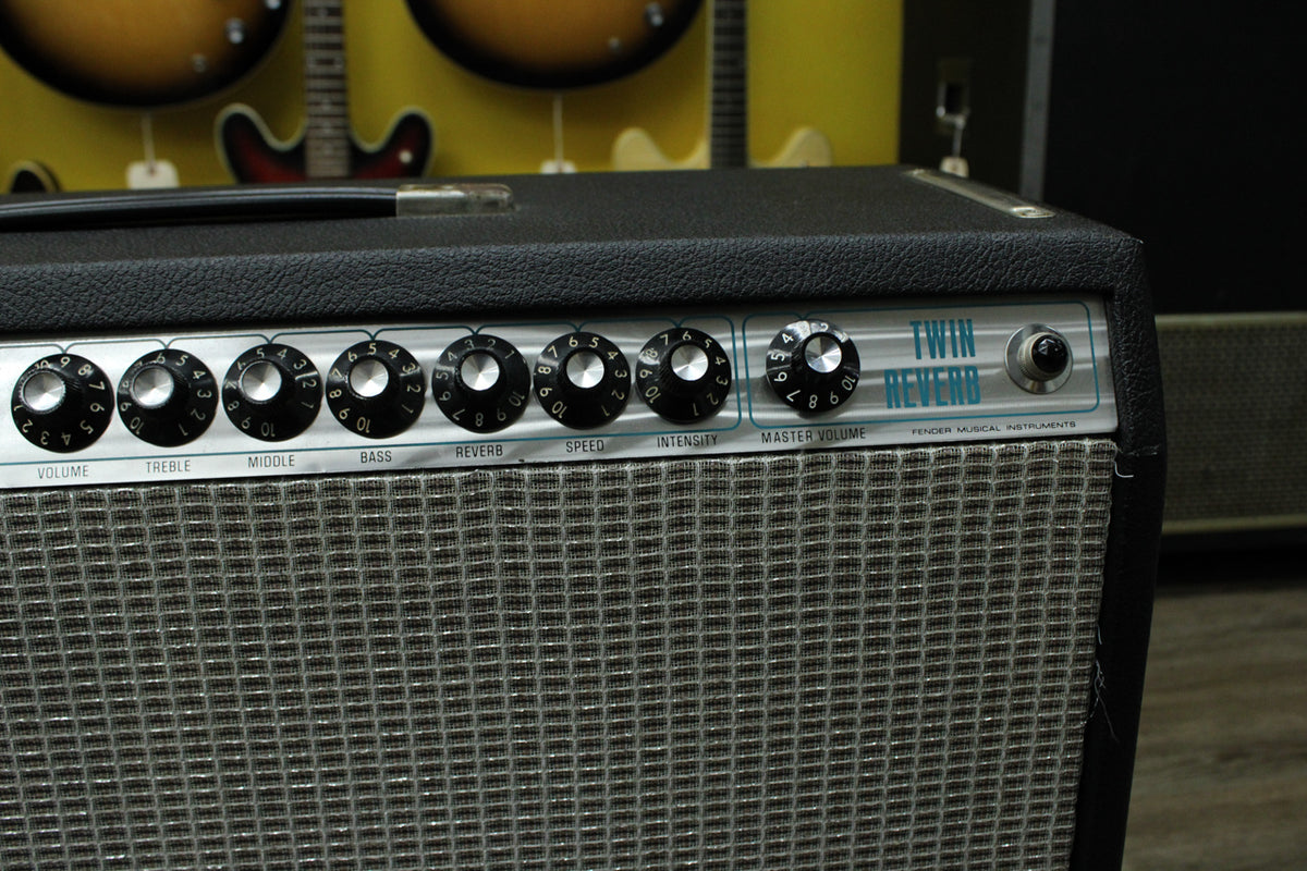Close-up of the amp's silver control panel and black knobs, with a silver grille cloth and black textured tolex visible below.