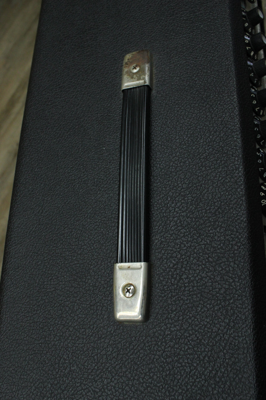 A close-up of the amp's black textured top, showing a black ribbed handle with tarnished silver-colored end caps.