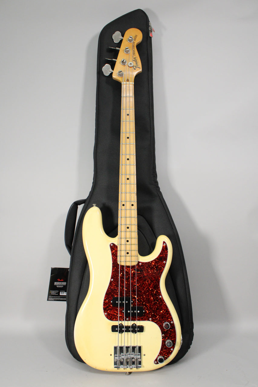 Full-length view of an Olympic White bass with a maple neck, red tortoise pickguard, and chrome hardware, standing in a black gig bag.