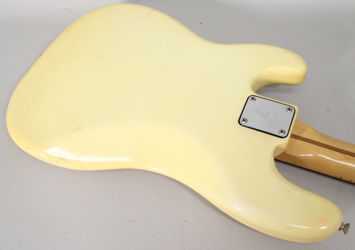 The back of the off-white bass body, showing a chrome neck plate, light wear and scratches, and a glimpse of the maple neck.