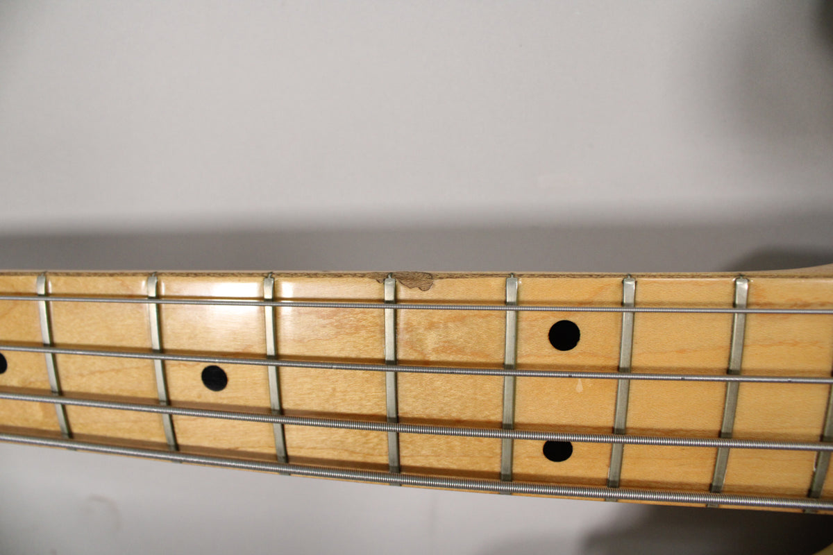 Close-up of the maple fretboard with black dot inlays, showing significant finish wear and chipping near the third fret.