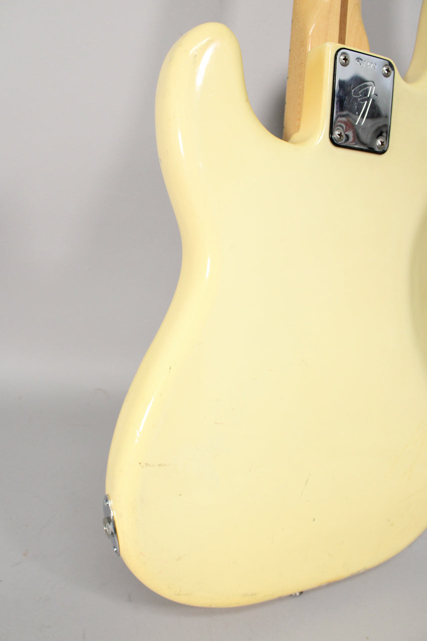 The back of an Olympic White bass body, showing a chrome neck plate, strap button, and visible wear and checking on the finish.