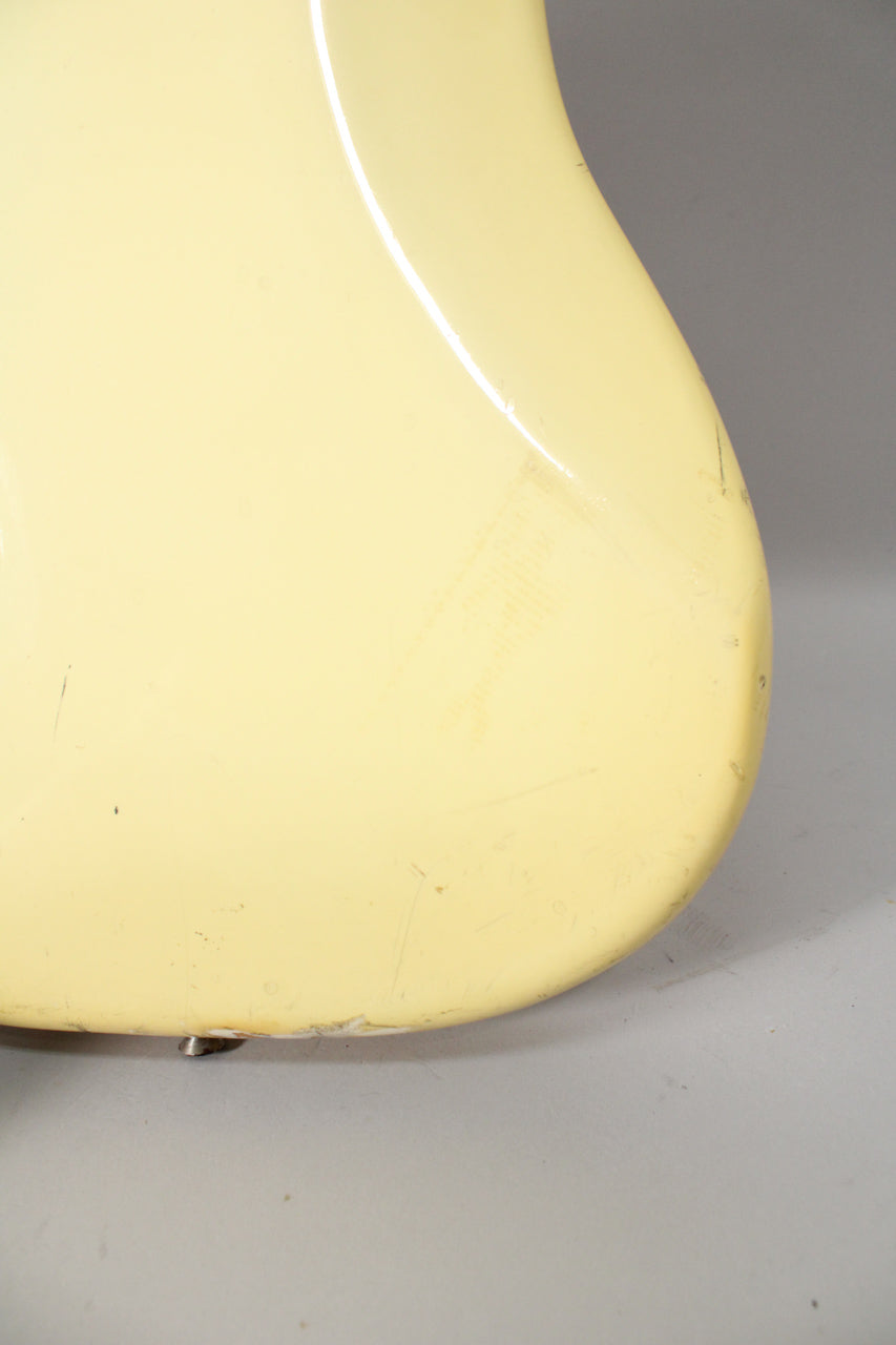 Close-up of the bass's lower bout in aged Olympic White, showing heavy scratching, scuffs, and chipped paint near the strap button.