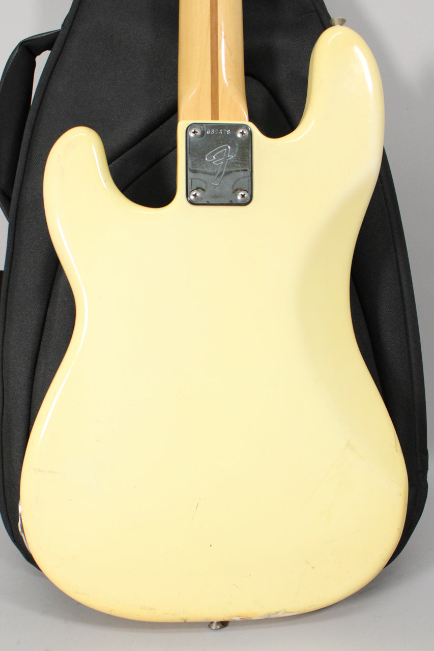 Rear view of an Olympic White bass body with a maple neck, chrome neck plate, and visible scratches and wear on the finish.