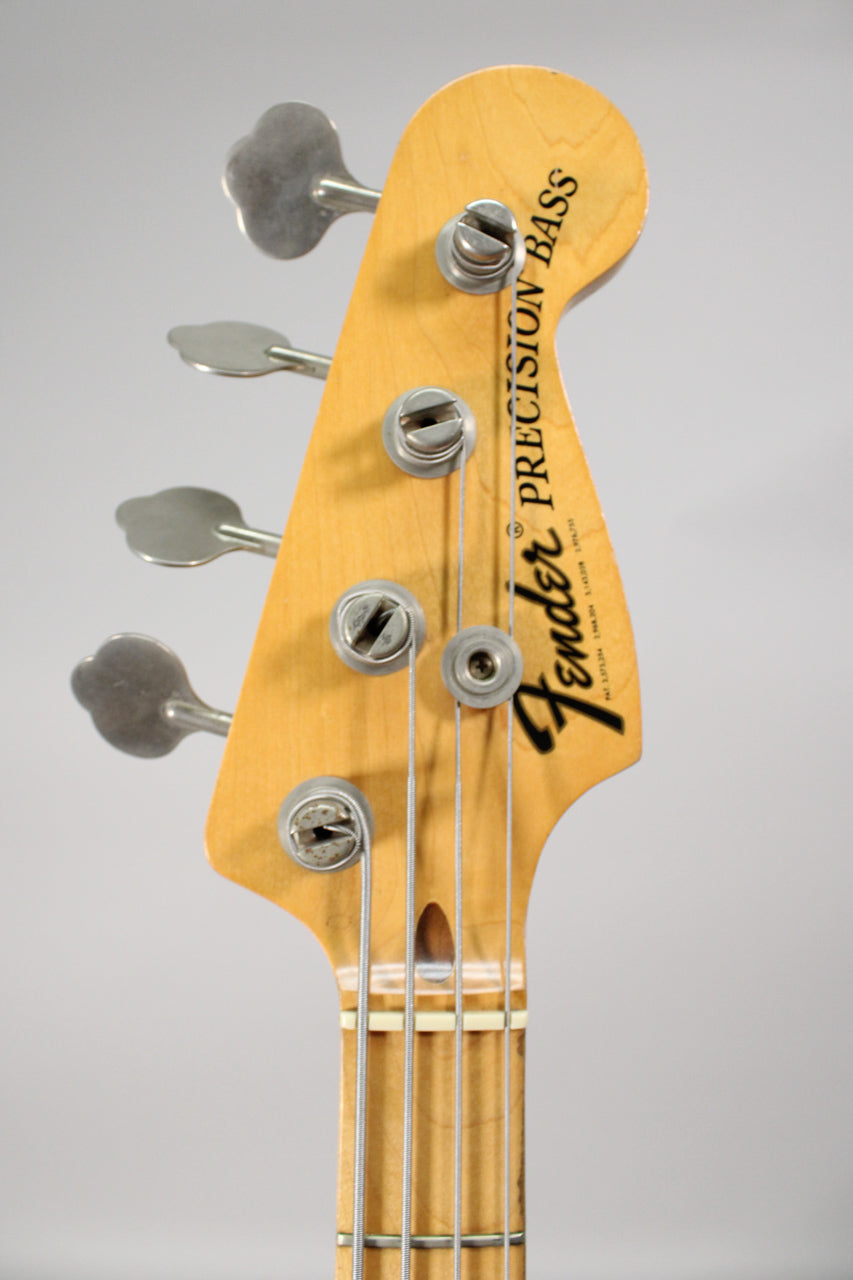 Close-up of the bass headstock, showing the maple finish, four clover-leaf tuners, and a string tree.