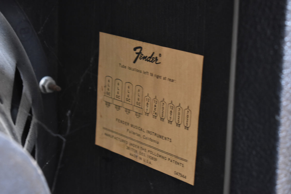 Close-up of the amp's rear, showing a faded tan tube chart sticker on the black textured cabinet, with a speaker frame visible left.