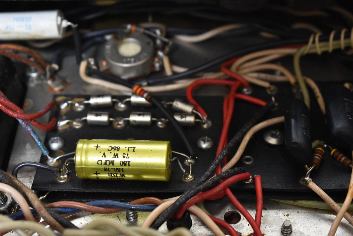 A close-up of the amplifier's internal wiring shows a yellow capacitor, resistors, and colorful wires on a black circuit board.