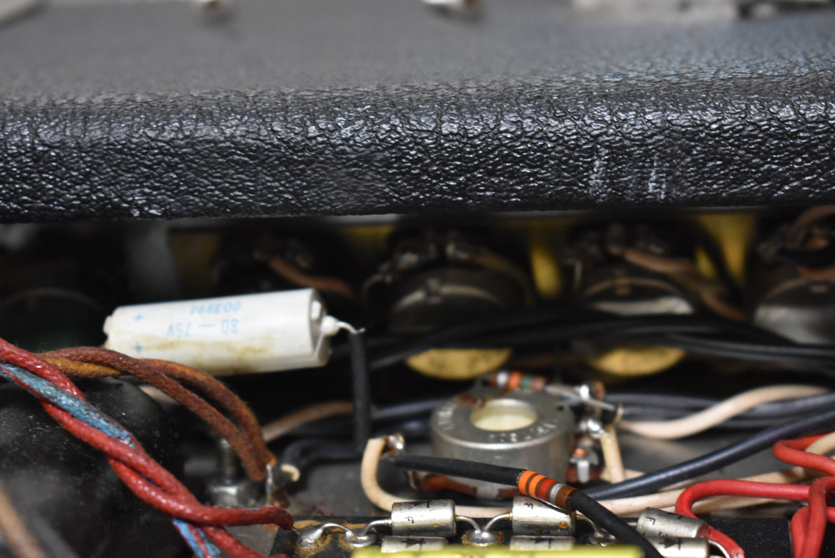 Close-up of the amplifier's internal wiring and components, showing a white capacitor, various resistors, and control pots.