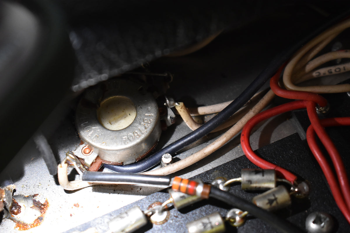 Close-up of internal wiring, showing a silver potentiometer with a cream center, surrounded by red, black, and beige wires.