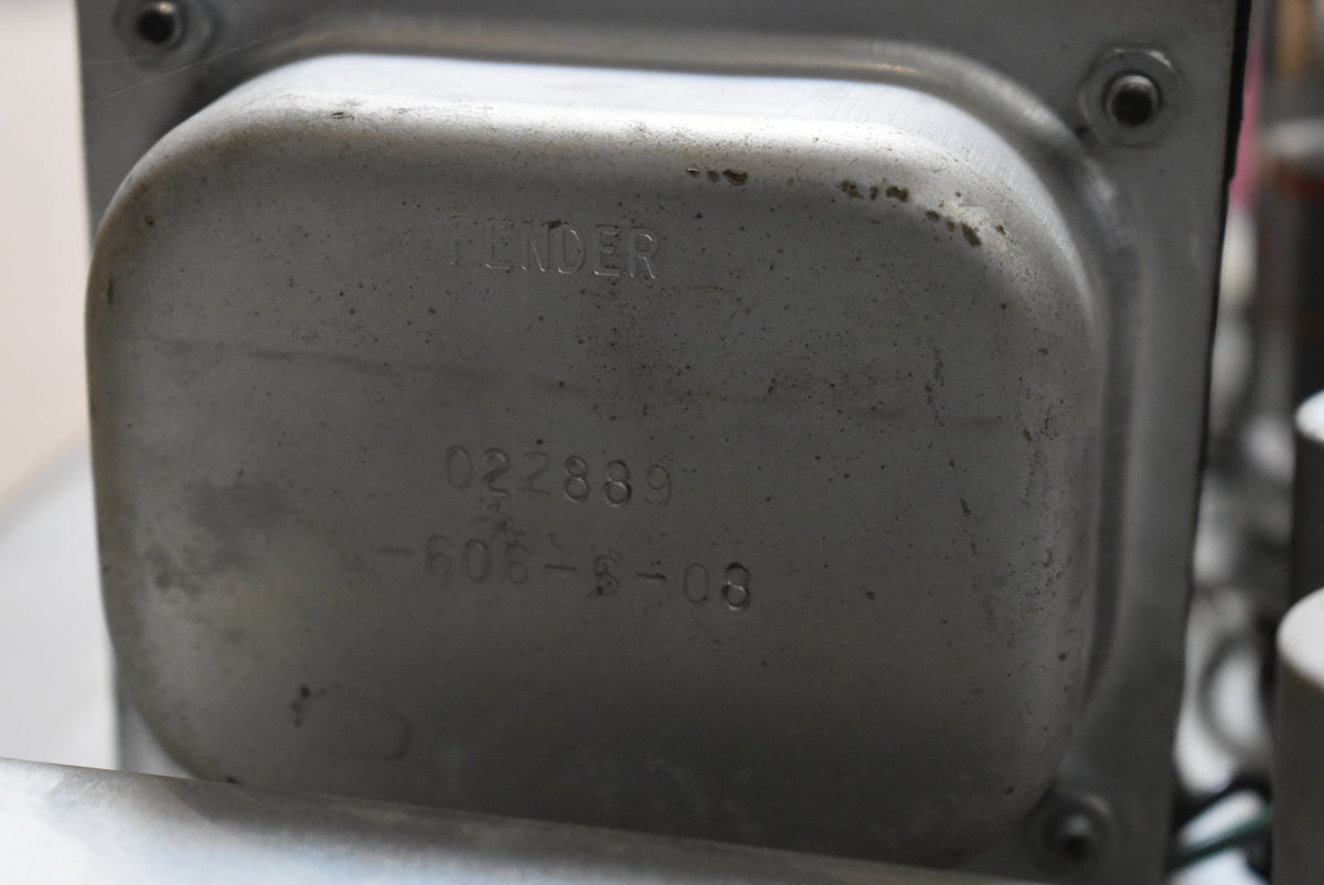 Close-up of the amp's silver-grey transformer, showing stamped numbers and light surface wear with small dark spots.