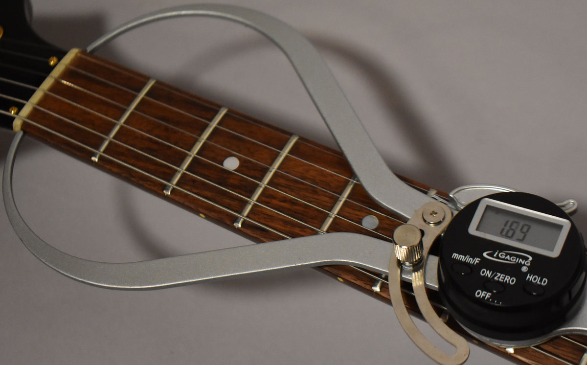 Close-up of the dark rosewood fretboard with a digital fret height gauge measuring 1.89mm on the 5th fret.
