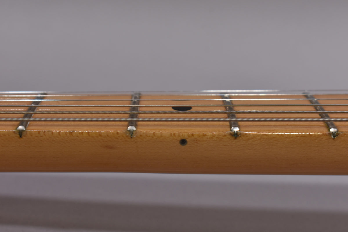 Close-up of the guitar's maple neck and fretboard, showing light wear and checking on the glossy finish, with dot inlays.