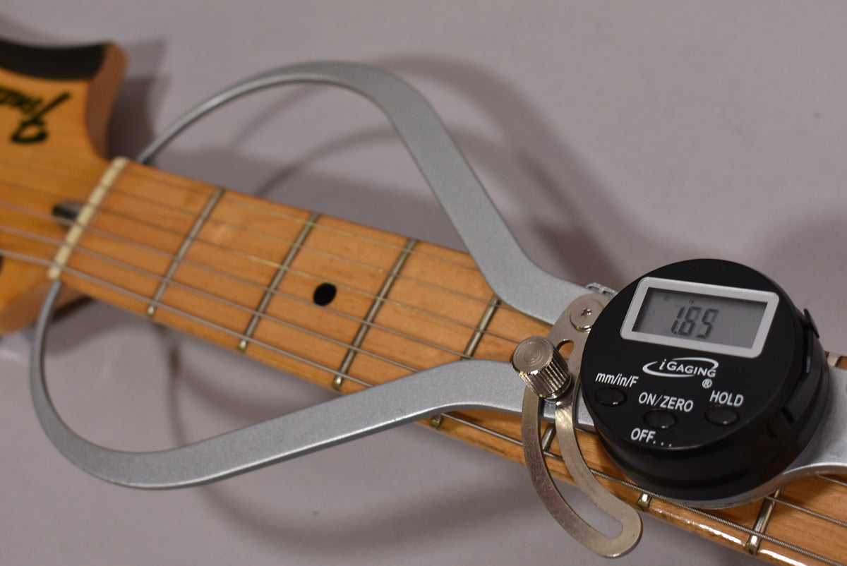 Close-up of the guitar's maple fretboard with a digital caliper measuring fret height at 1.89mm, showing light wear on the frets.