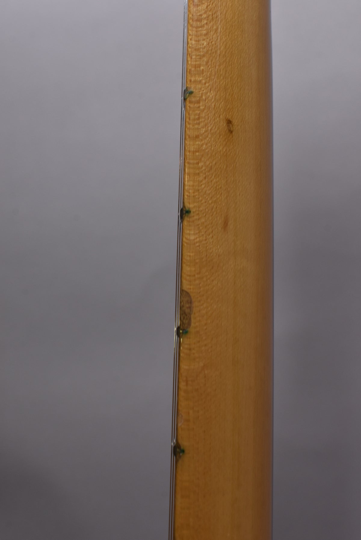 Close-up of the guitar's natural flame maple neck, showing wear and a dark spot on the bass side, with green fret markers.