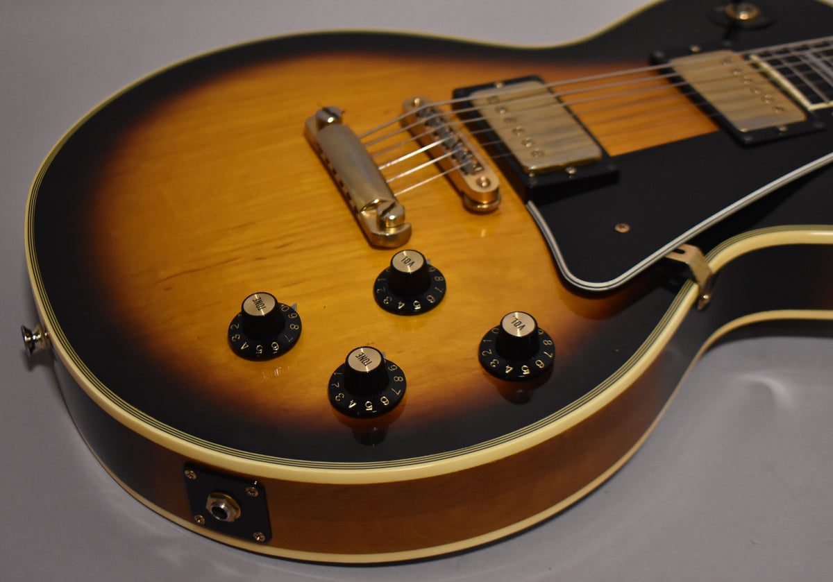 The tobacco sunburst body, with cream binding, shows light wear and features four black "top hat" knobs and gold hardware.