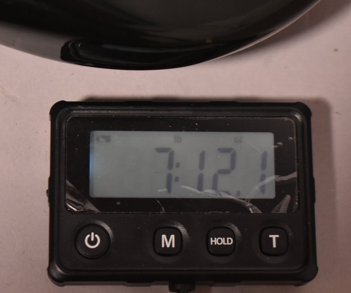 Digital scale displaying 7 lbs 12.1 oz, with a portion of the black guitar body visible at the top.