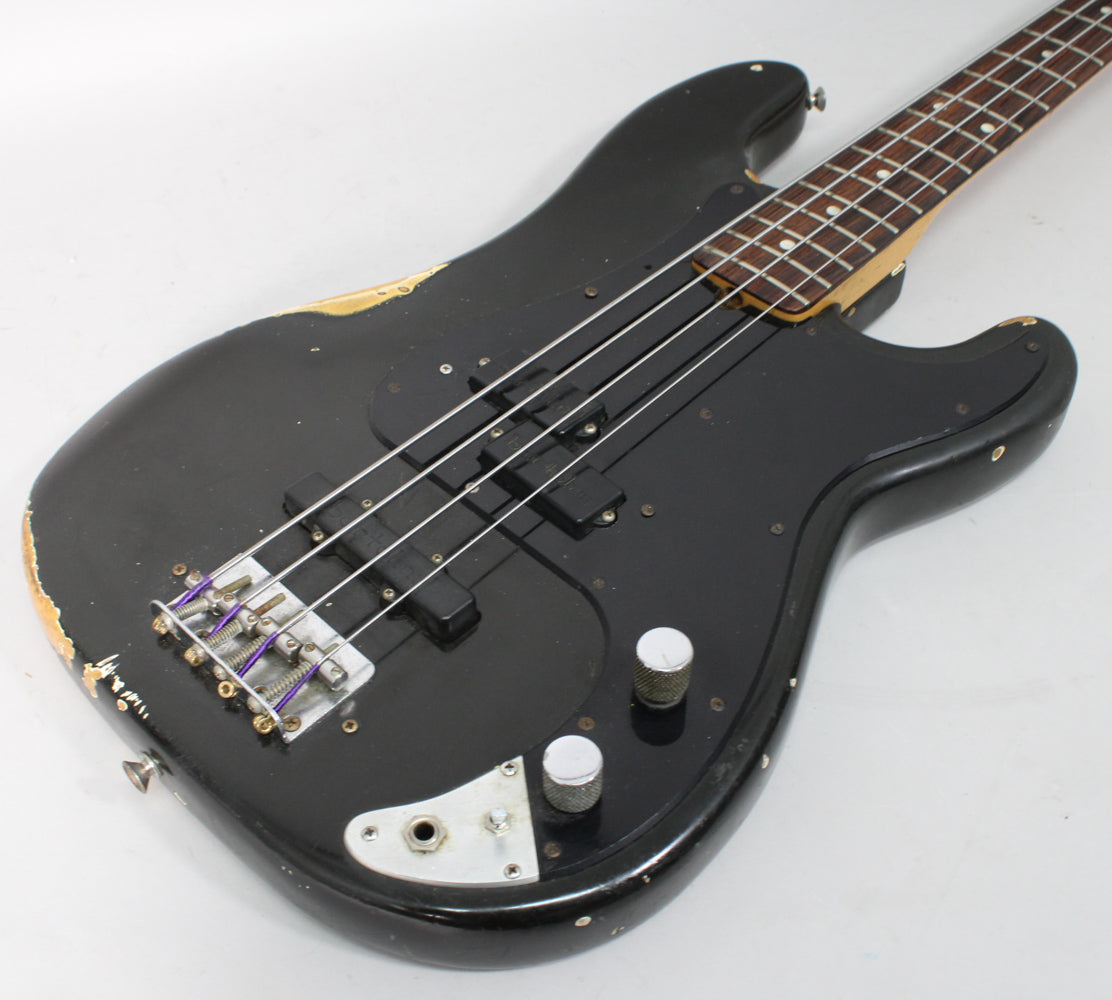 Black bass guitar, angled view of the body and neck, showing two black pickups, chrome bridge, and two silver control knobs.