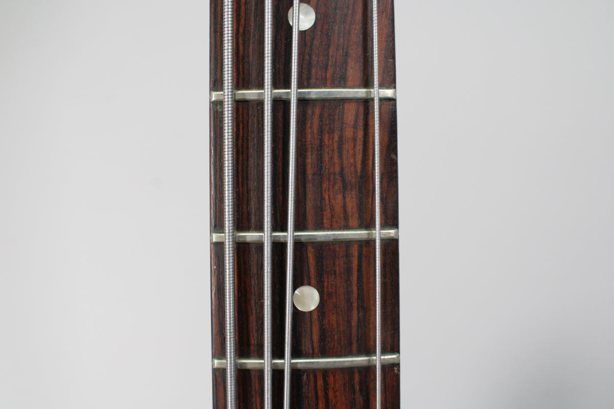 Close-up of the dark rosewood fretboard with four strings, silver frets, and two mother-of-pearl dot inlays.
