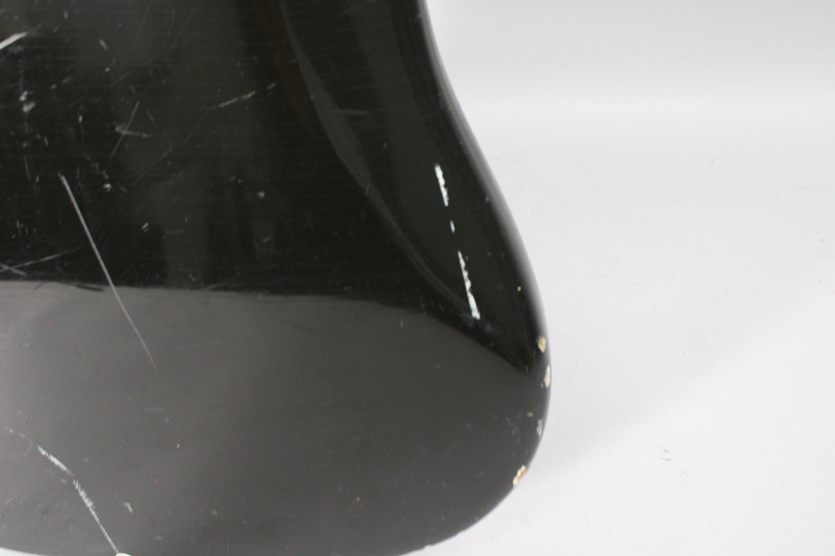 Close-up of the bass's lower bout, showing heavy scratching and several chips in the black finish revealing white undercoat.