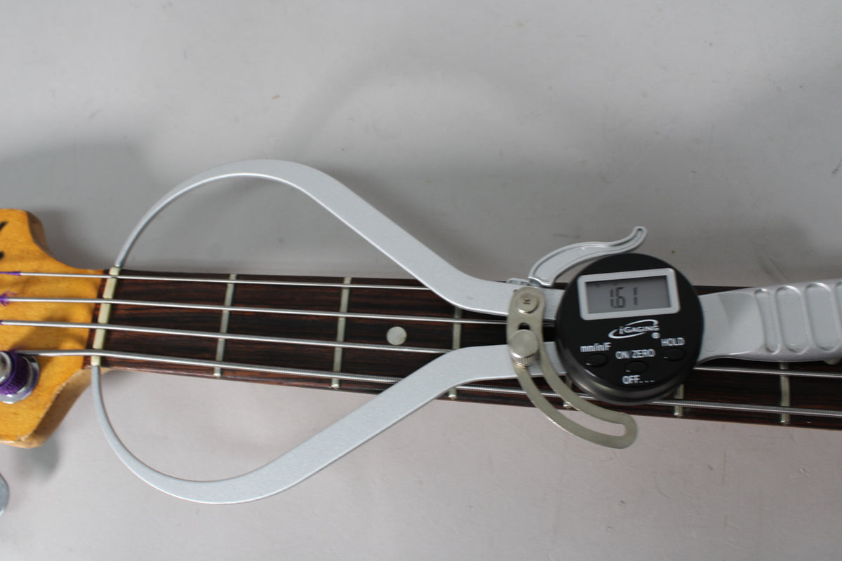 A digital caliper measures the string height at the 12th fret of the dark rosewood fretboard, showing 1.61mm.
