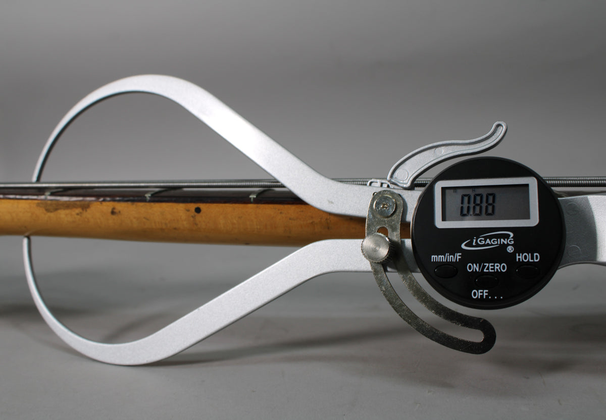A digital string action gauge measures the bass's strings above the worn, amber-tinted maple neck, displaying "0.88".