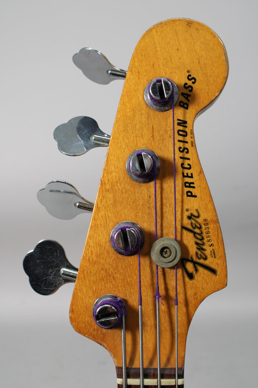 Close-up of the bass headstock, showing the worn maple finish, four chrome clover-leaf tuners, and purple strings.