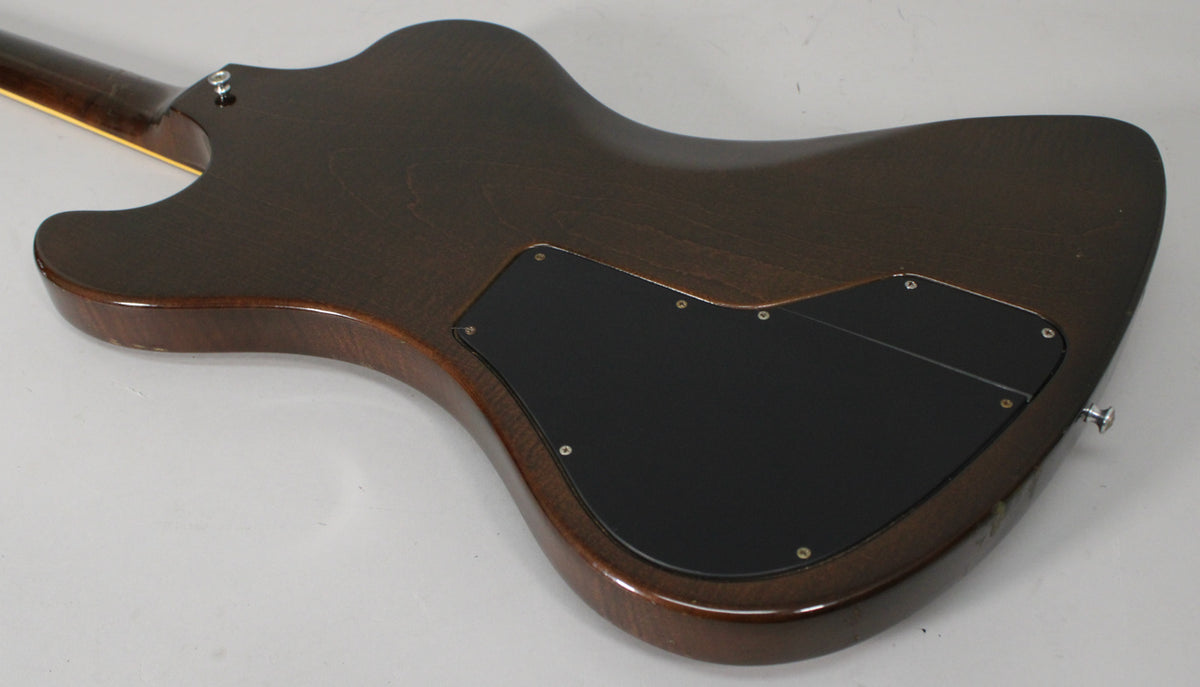 The back of the dark walnut guitar body, showing the two black control cavity covers and a chrome strap button.
