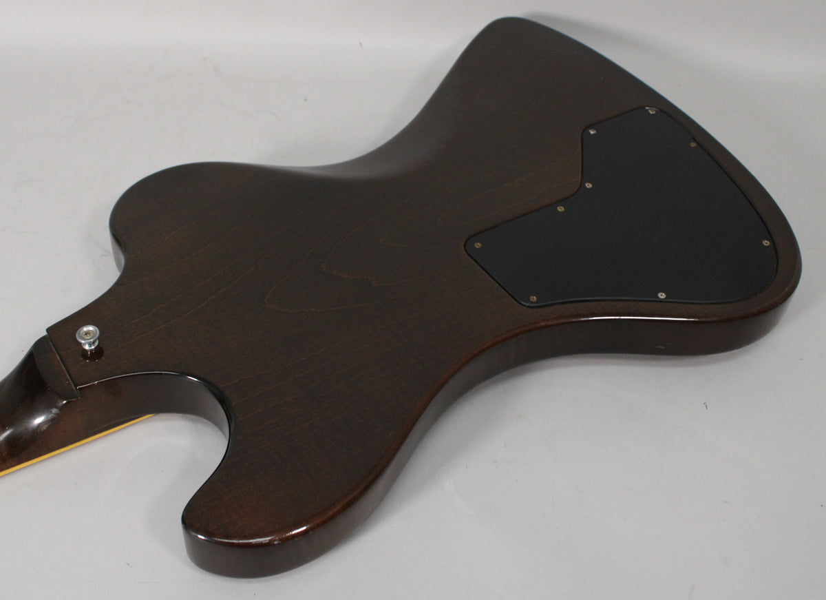 The back of the dark walnut guitar body, angled from the neck joint to the lower bout, shows a black control cavity cover.