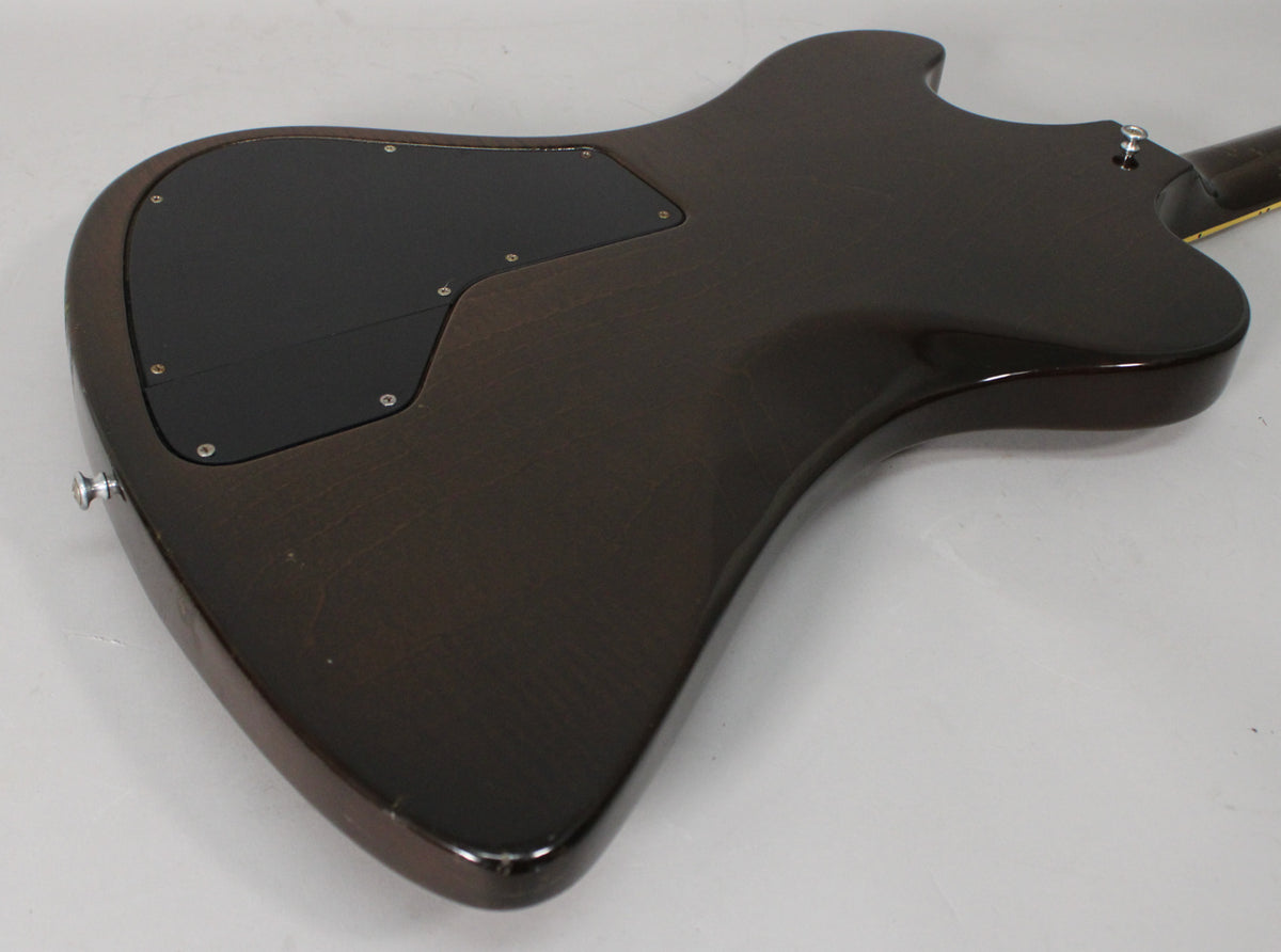 The guitar's dark walnut body, seen from the back, has a large black control cavity cover and visible finish wear and scratches.
