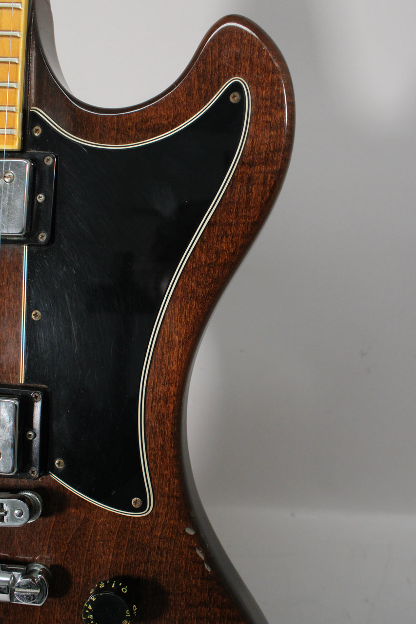 Close-up of the guitar's upper body, showing the walnut finish, black pickguard with white binding, and chrome humbucker.