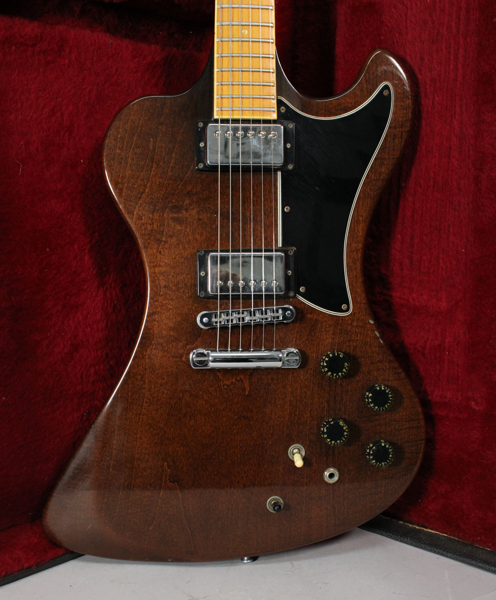 Full body shot of a dark walnut electric guitar with a black pickguard, two humbuckers, and four black control knobs.
