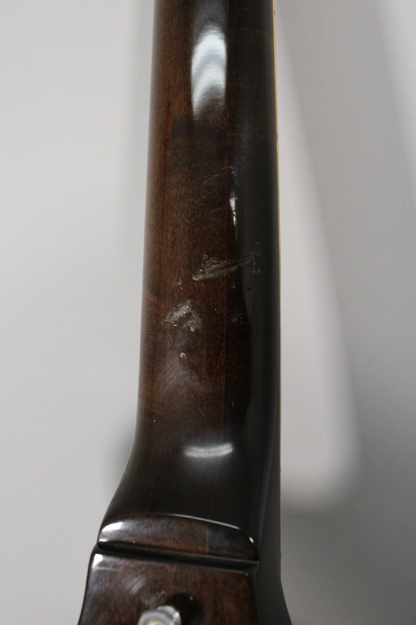 Close-up of the guitar's dark walnut neck, showing significant finish wear and several chips near the heel.