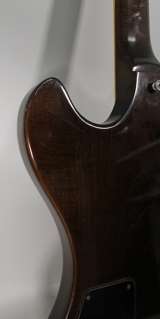The guitar's dark walnut body, with visible wood grain and some finish checking, curves towards the neck joint.