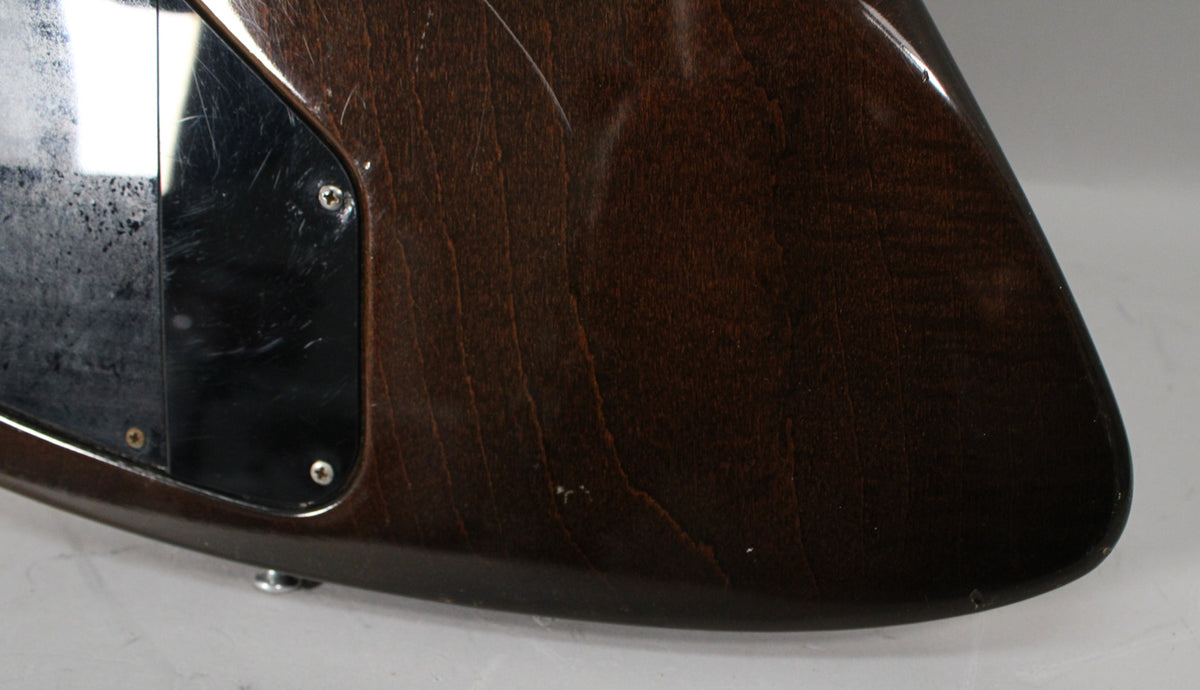 Close-up of the guitar's lower bout, showing the dark walnut finish with visible wood grain, scratches, and a black control plate.
