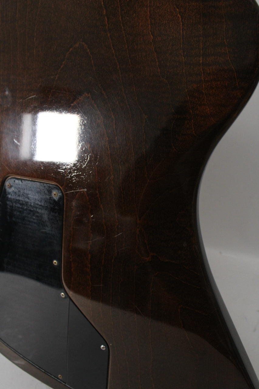 Close-up of the guitar's dark walnut body, showing a black control cavity cover and light surface scratches near a bright reflection.