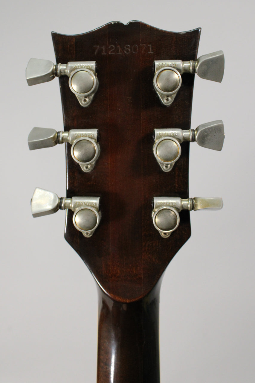 Rear view of the dark walnut headstock and neck, showing six worn silver tuners and a serial number stamped at the top.
