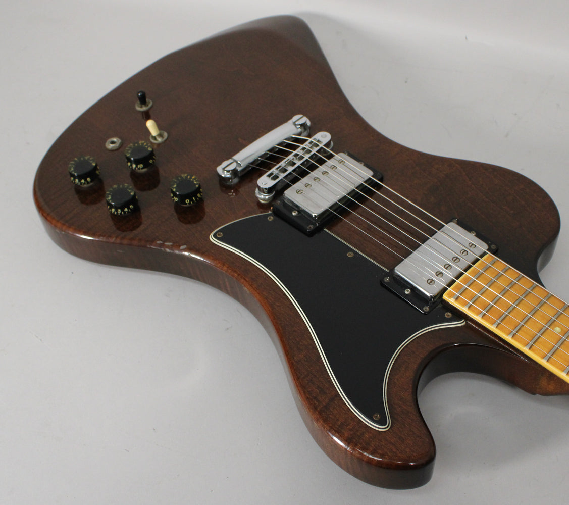 Angled close-up of the dark walnut body, showing the black pickguard, chrome humbuckers, four black control knobs, and a three-way switch.