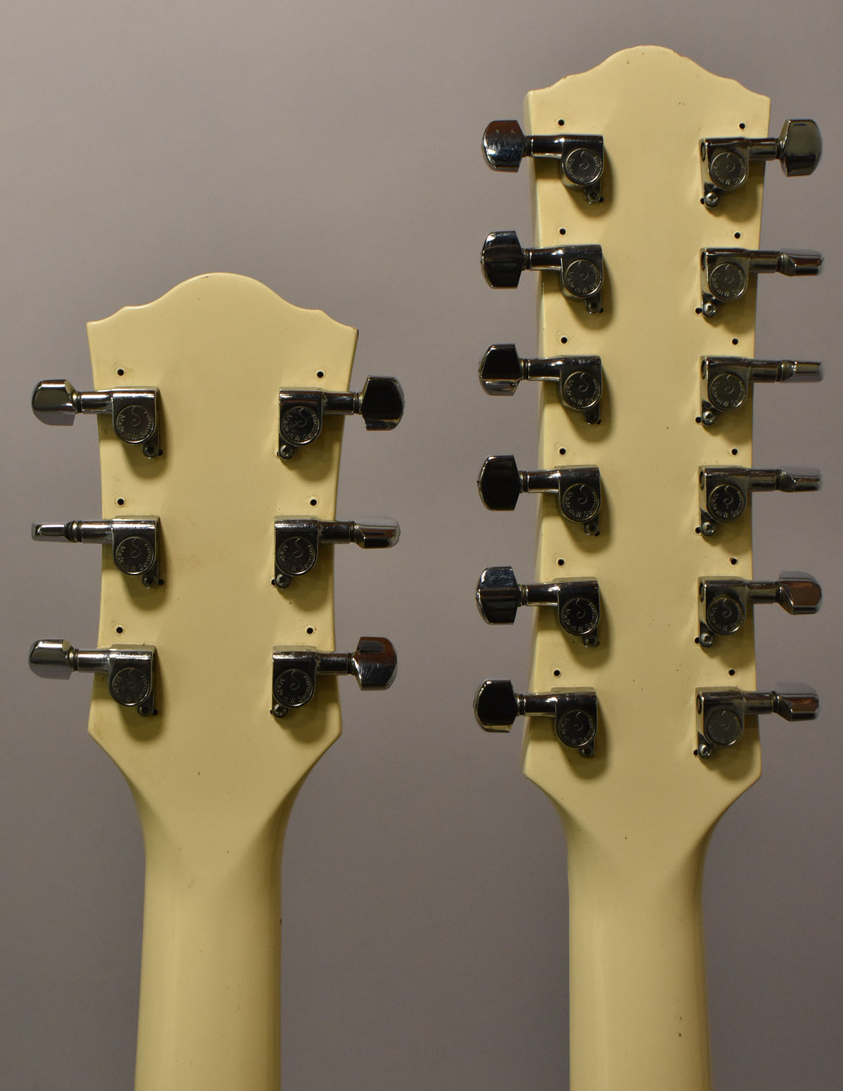 Rear view of two cream-colored headstocks with chrome tuners; the left has 6 tuners, the right has 12.